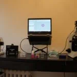 two microscopes, a laptop, and an air sampler