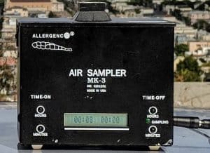 A black brick-sized air sampler with time controls